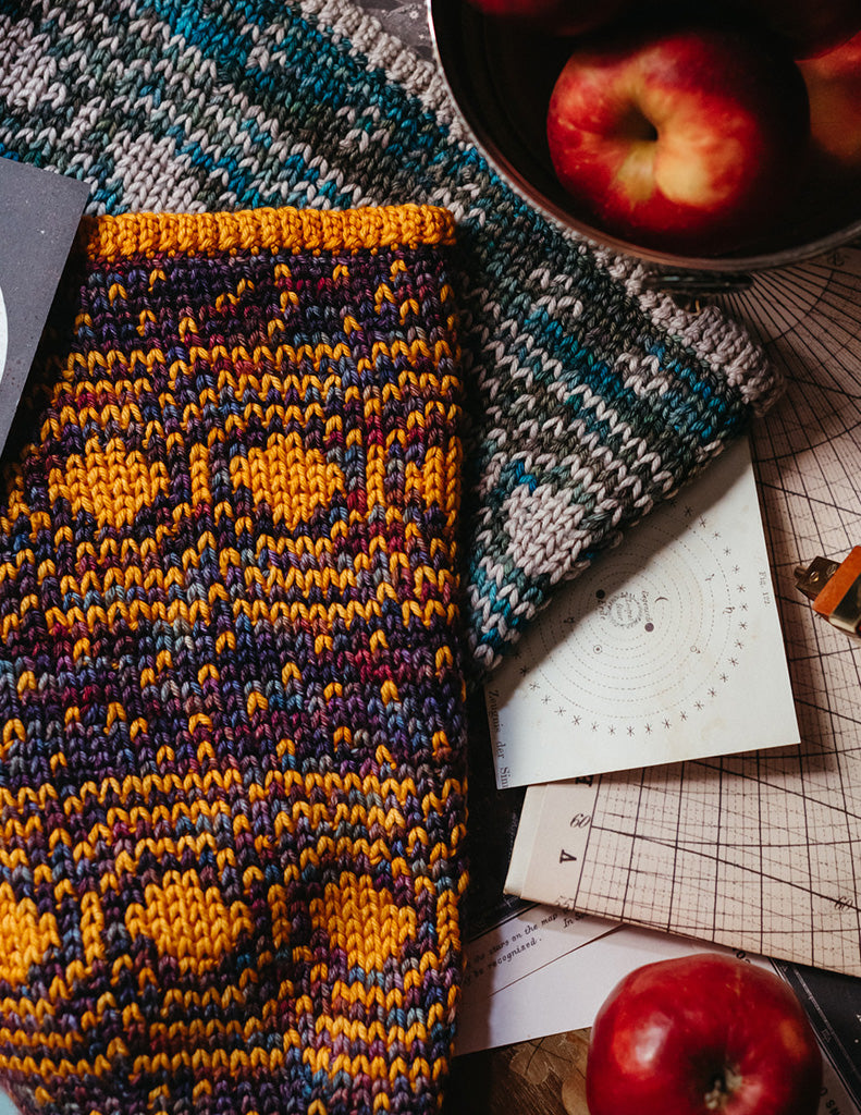 The Connected Cosmos cowl is a snug knit-look colourwork cowl. The main motif features circles surrounded by concentric rings.